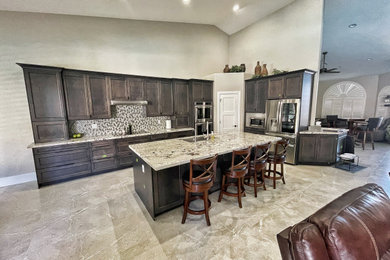 Open concept kitchen - large transitional l-shaped porcelain tile and beige floor open concept kitchen idea in Phoenix with an undermount sink, shaker cabinets, dark wood cabinets, granite countertops, multicolored backsplash, glass tile backsplash, stainless steel appliances, an island and beige countertops