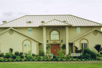 Inspiration for a large mediterranean beige two-story stucco house exterior remodel in Oklahoma City with a hip roof and a metal roof