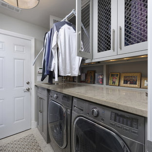 ワシントンD.C.の中サイズのトランジショナルスタイルのおしゃれな家事室 (アンダーカウンターシンク、シェーカースタイル扉のキャビネット、グレーのキャビネット、ライムストーンカウンター、グレーの壁、大理石の床、左右配置の洗濯機・乾燥機、グレーの床、グレーのキッチンカウンター) の写真