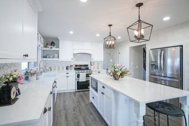 Elegant l-shaped dark wood floor and brown floor kitchen photo in Denver with a farmhouse sink, shaker cabinets, white cabinets, multicolored backsplash, stainless steel appliances, an island and white countertops