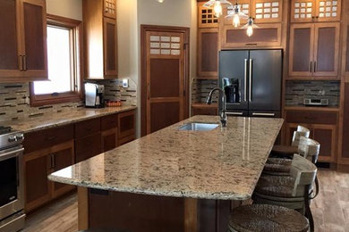 Eat-in kitchen - large transitional l-shaped eat-in kitchen idea in Other with a single-bowl sink, brown cabinets, granite countertops, brown backsplash, stainless steel appliances and an island