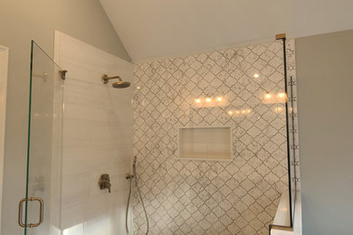 Example of a large trendy master beige tile and porcelain tile porcelain tile, white floor and double-sink bathroom design in Boston with a built-in vanity, furniture-like cabinets, brown cabinets, a two-piece toilet, gray walls, an undermount sink, quartz countertops, a hinged shower door, beige countertops and a niche