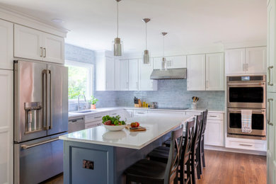 Inspiration for a mid-sized transitional l-shaped medium tone wood floor eat-in kitchen remodel in New York with an undermount sink, shaker cabinets, white cabinets, quartz countertops, blue backsplash, porcelain backsplash, stainless steel appliances, an island and white countertops