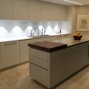 Idées déco pour une arrière-cuisine parallèle moderne de taille moyenne avec un placard à porte plane, des portes de placard blanches, un électroménager en acier inoxydable, un îlot central, un évier encastré, un plan de travail en granite et un sol en travertin.