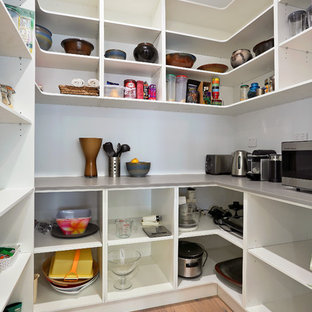 Cette photo montre une arrière-cuisine parallèle moderne de taille moyenne avec un évier encastré, un placard à porte plane, des portes de placard blanches, un plan de travail en quartz modifié, une crédence blanche, une crédence en fenêtre, un électroménager en acier inoxydable, un sol en bois clair, un îlot central et un sol marron.