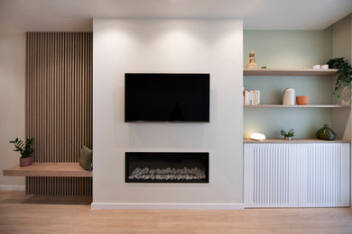 Diseño de salón abierto y blanco y madera nórdico grande con paredes verdes, suelo de madera en tonos medios, televisor colgado en la pared, suelo marrón y panelado