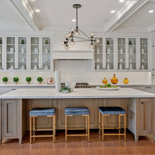 Ejemplo de cocina en U y gris y blanca, campestre, de tamaño medio, abierta, con fregadero sobremueble, armarios estilo shaker, puertas de armario de madera clara, encimera de mármol, salpicadero blanco, salpicadero de azulejos tipo metro, electrodomésticos de acero inoxidable, suelo de madera en tonos medios, una isla, suelo marrón y encimeras blancas