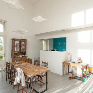 Idées déco pour une salle à manger ouverte sur le salon contemporaine de taille moyenne avec un mur blanc et béton au sol.