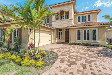 Example of a large tuscan beige two-story stucco house exterior design in Miami