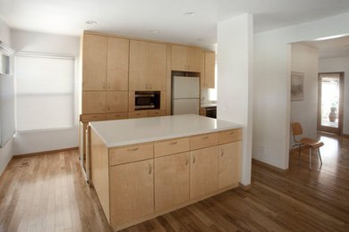 Small trendy galley medium tone wood floor and brown floor eat-in kitchen photo in Los Angeles with a double-bowl sink, flat-panel cabinets, light wood cabinets, quartz countertops, white backsplash, stone slab backsplash, black appliances and an island