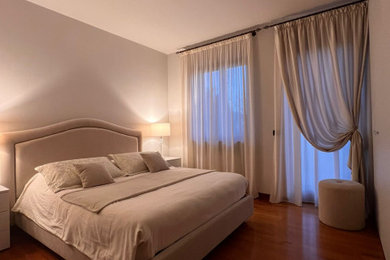 Foto di una camera matrimoniale minimal con pareti beige, pavimento in legno verniciato e pavimento marrone