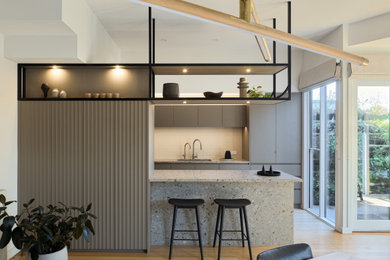 Photo of a small contemporary eat-in kitchen in Melbourne with a double-bowl sink, flat-panel cabinets, grey cabinets, terrazzo benchtops, grey splashback, ceramic splashback, black appliances, light hardwood floors, with island and multi-coloured benchtop.