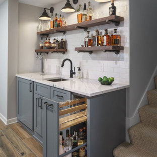 Diseño de bar en casa con fregadero lineal, de estilo de casa de campo, de tamaño medio, con suelo de baldosas de porcelana, suelo marrón, fregadero bajoencimera, armarios estilo shaker, puertas de armario grises, encimera de cuarzo compacto, salpicadero blanco, salpicadero de azulejos de cerámica y encimeras blancas