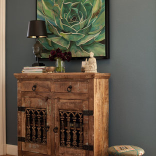 Aménagement d'un petit hall d'entrée éclectique avec un mur bleu, un sol en bois brun, une porte simple et une porte blanche.