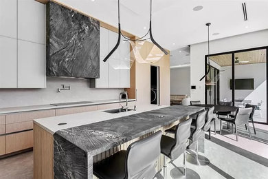 This is an example of a modern kitchen in Miami with a submerged sink, flat-panel cabinets, light wood cabinets, stainless steel appliances and an island.