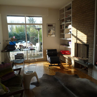 Inspiration for a medium sized modern study in Paris with white walls, a standard fireplace, a brick fireplace surround, medium hardwood flooring and a freestanding desk.