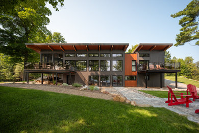 Example of a large trendy gray two-story wood and clapboard house exterior design in Montreal with a butterfly roof, a mixed material roof and a gray roof