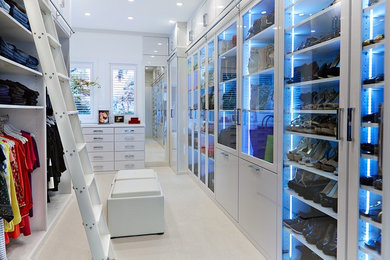 Example of a huge trendy gender-neutral carpeted and beige floor dressing room design in Tampa with white cabinets and glass-front cabinets