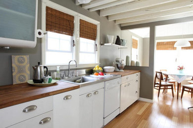 Mid-sized trendy light wood floor and beige floor eat-in kitchen photo in Salt Lake City with an integrated sink, flat-panel cabinets, white cabinets, wood countertops, white appliances and brown countertops
