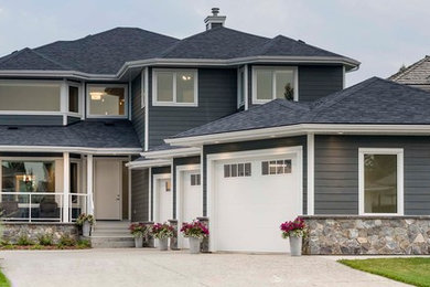 Example of a large transitional gray two-story concrete fiberboard house exterior design in Edmonton with a hip roof