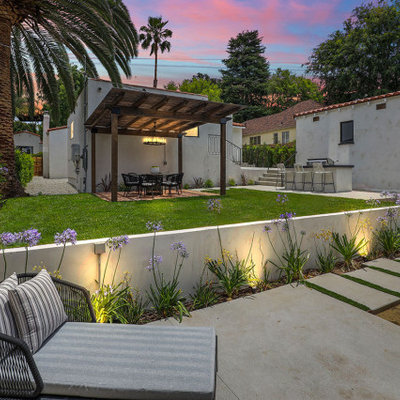 Inspiration for a mid-sized transitional backyard concrete paver and wood fence retaining wall landscape in Los Angeles with a fire pit.