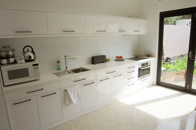 Design ideas for a mid-sized contemporary single-wall eat-in kitchen in Perth with white cabinets, white splashback, glass sheet splashback, concrete floors and no island.