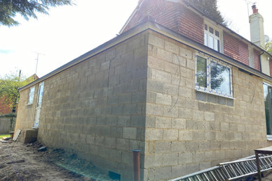 Aménagement d'une façade de maison blanche contemporaine en stuc de taille moyenne et à un étage avec un toit à deux pans, un toit en tuile et un toit marron.