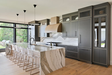 Inspiration for a large modern single-wall eat-in kitchen in Atlanta with an undermount sink, flat-panel cabinets, grey cabinets, quartz benchtops, white splashback, engineered quartz splashback, panelled appliances, light hardwood floors, with island, brown floor and white benchtop.