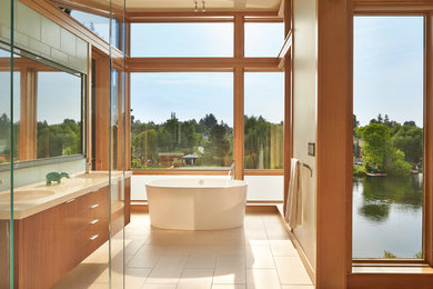 Photo of a mid-sized modern master bathroom in Seattle with flat-panel cabinets, medium wood cabinets, a freestanding tub, a curbless shower, a one-piece toilet, glass tile, porcelain floors, an undermount sink and engineered quartz benchtops.