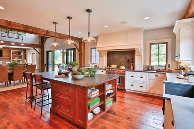 Example of a mid-sized arts and crafts u-shaped medium tone wood floor eat-in kitchen design in Denver with a farmhouse sink, white cabinets, concrete countertops, black backsplash, cement tile backsplash, black appliances, an island and shaker cabinets