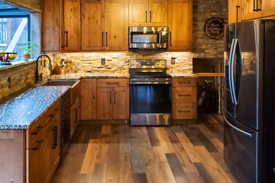 Eat-in kitchen - mid-sized rustic l-shaped brown floor and laminate floor eat-in kitchen idea in Chicago with a farmhouse sink, beige backsplash, stone tile backsplash, stainless steel appliances, medium tone wood cabinets, granite countertops and multicolored countertops