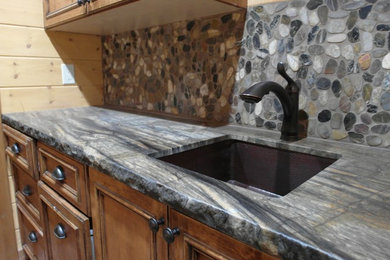 Inspiration for a mid-sized rustic single-wall open concept kitchen remodel in Phoenix with an undermount sink, medium tone wood cabinets, marble countertops, multicolored backsplash, stone tile backsplash, black appliances and recessed-panel cabinets