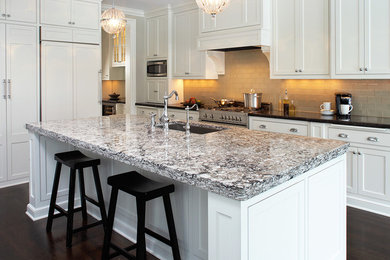 Inspiration for a large timeless l-shaped dark wood floor and brown floor open concept kitchen remodel in Little Rock with an undermount sink, shaker cabinets, white cabinets, granite countertops, beige backsplash, subway tile backsplash, paneled appliances and an island