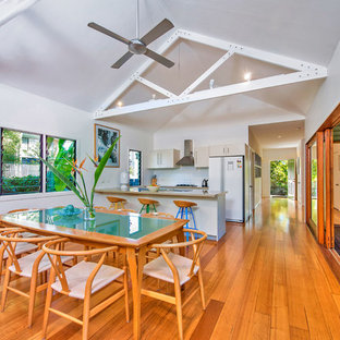 Photo of a tropical open plan dining in Gold Coast - Tweed with white walls and medium hardwood floors.