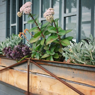 Foto de fachada de casa gris, industrial, pequeña, de una planta, con revestimiento de ladrillo, tejado a dos aguas y tejado de teja de barro