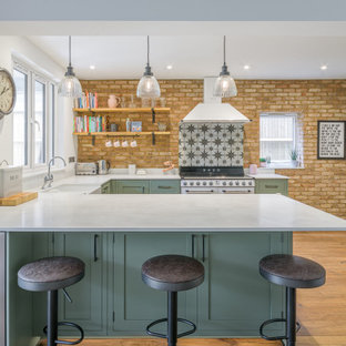 This is an example of a medium sized traditional u-shaped open plan kitchen in Sussex with a breakfast bar and white worktops.