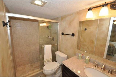 Alcove shower - mid-sized traditional master ceramic tile alcove shower idea in Miami with raised-panel cabinets, dark wood cabinets, a two-piece toilet, beige walls, an undermount sink and laminate countertops