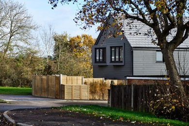 Inspiration for a large and gey contemporary bungalow detached house in London with concrete fibreboard cladding, a pitched roof, a tiled roof, a grey roof and board and batten cladding.