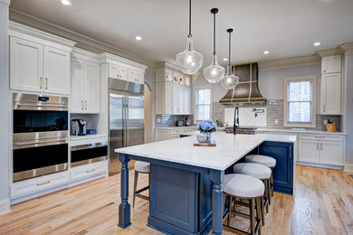 Mid-sized transitional l-shaped medium tone wood floor and beige floor enclosed kitchen photo in Indianapolis with an undermount sink, shaker cabinets, white cabinets, granite countertops, gray backsplash, subway tile backsplash, stainless steel appliances, an island and white countertops