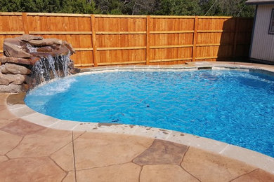 Inspiration for a mid-sized traditional backyard custom-shaped natural pool in Dallas with a hot tub and stamped concrete.