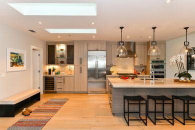 Open concept kitchen - huge transitional galley light wood floor and beige floor open concept kitchen idea in San Francisco with a drop-in sink, flat-panel cabinets, gray cabinets, quartzite countertops, white backsplash, marble backsplash, stainless steel appliances, an island and white countertops