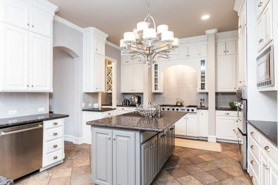 Inspiration for a large timeless u-shaped slate floor eat-in kitchen remodel in Dallas with an undermount sink, raised-panel cabinets, white cabinets, granite countertops, gray backsplash, porcelain backsplash, stainless steel appliances and an island