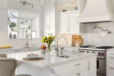 Inspiration for a medium sized traditional u-shaped kitchen/diner in San Diego with a submerged sink, recessed-panel cabinets, white cabinets, engineered stone countertops, white splashback, engineered quartz splashback, stainless steel appliances, vinyl flooring, an island, brown floors and white worktops.