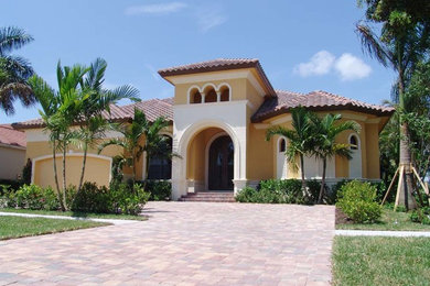 Example of a mid-sized tuscan yellow two-story stucco exterior home design in Miami
