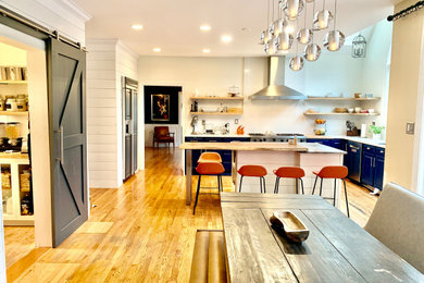Inspiration for a large farmhouse l-shaped light wood floor, brown floor and vaulted ceiling eat-in kitchen remodel in Philadelphia with an undermount sink, raised-panel cabinets, blue cabinets, quartzite countertops, white backsplash, quartz backsplash, stainless steel appliances, an island and blue countertops