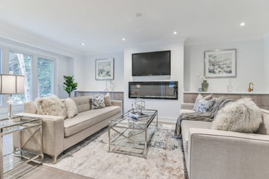 Foto de sala de estar abierta contemporánea grande con paredes grises, suelo de madera clara, televisor colgado en la pared y suelo beige