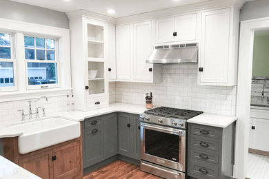 Mid-sized elegant u-shaped medium tone wood floor and brown floor eat-in kitchen photo in Detroit with a farmhouse sink, beaded inset cabinets, white cabinets, quartz countertops, white backsplash, subway tile backsplash, stainless steel appliances, a peninsula and white countertops