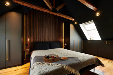 Großes Schlafzimmer mit blauer Wandfarbe, braunem Holzboden, braunem Boden, freigelegten Dachbalken und Holzwänden in Hamburg