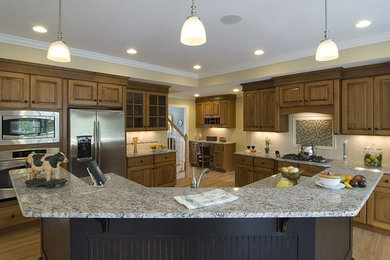 Example of a large classic l-shaped medium tone wood floor and brown floor kitchen design in Other with an undermount sink, raised-panel cabinets, medium tone wood cabinets, granite countertops, white backsplash, subway tile backsplash, stainless steel appliances, an island and multicolored countertops