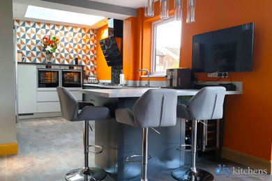 Стильный дизайн: угловая кухня среднего размера в стиле модернизм с обеденным столом, плоскими фасадами, серыми фасадами, столешницей из ламината, полуостровом и белой столешницей - последний тренд